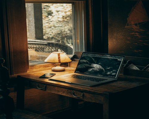 A modern setup with a laptop showing document drafts under a soft lateral window light